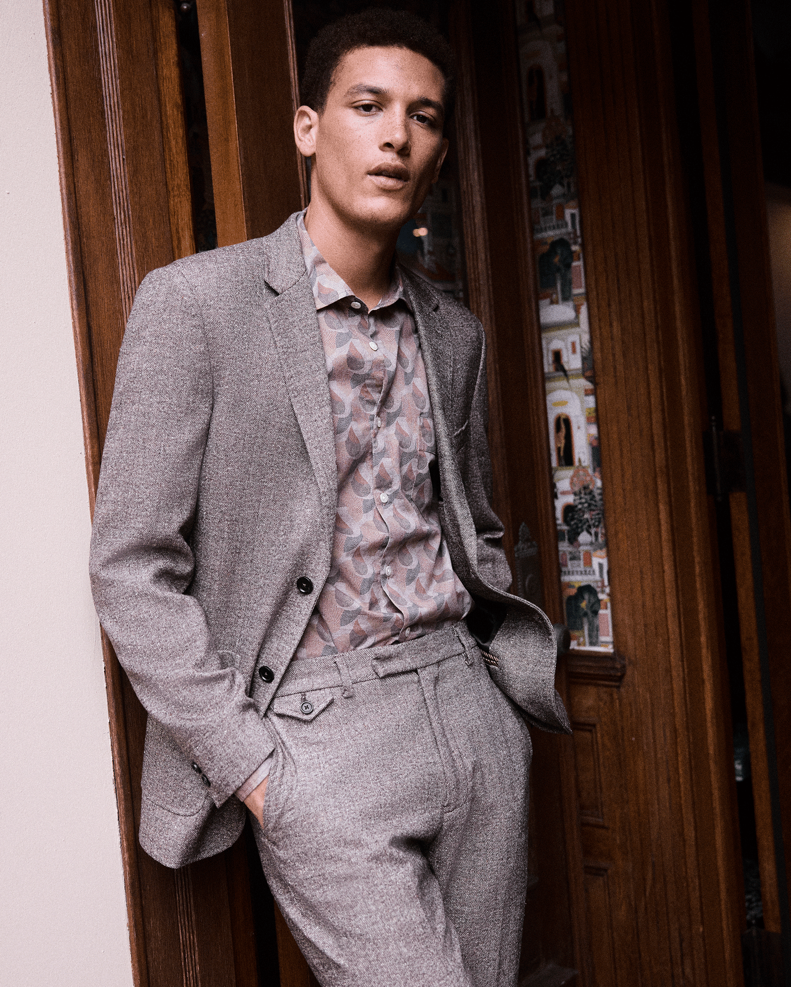Man wearing a gray suit with a patterned shirt in an indoor setting