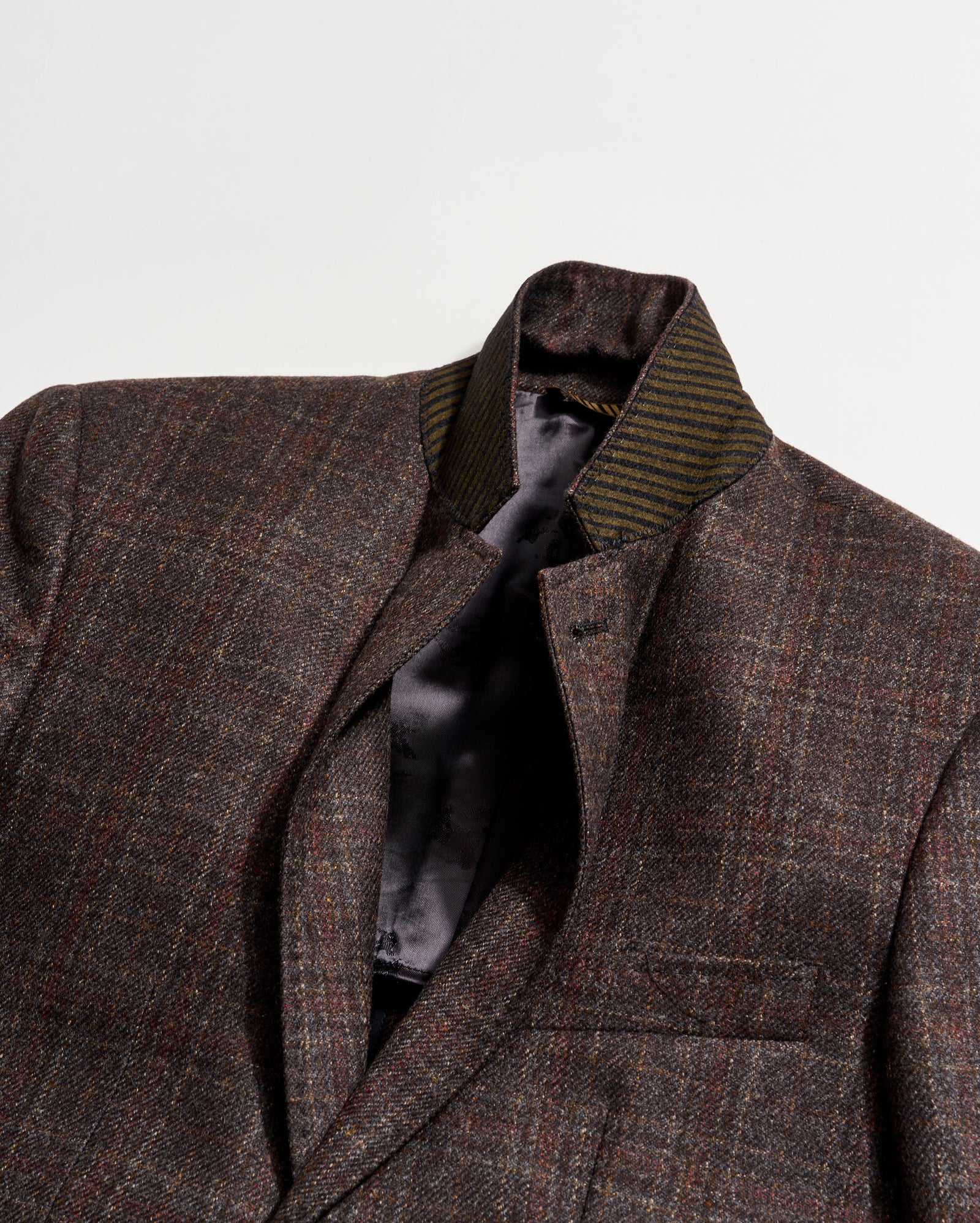 Brown checkered blazer with a striped tie on a light gray background