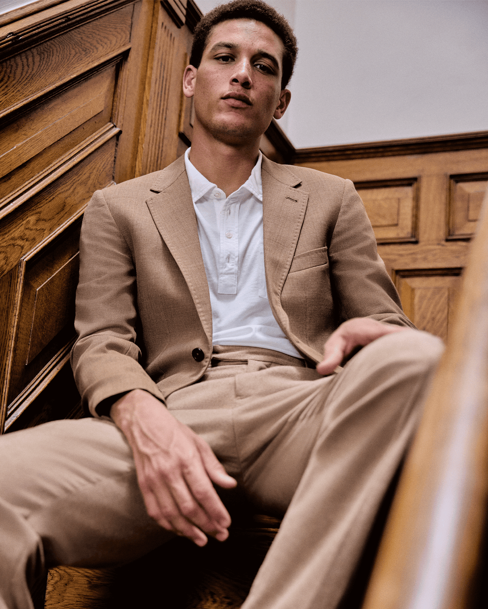 Man in a beige suit sitting on a staircase