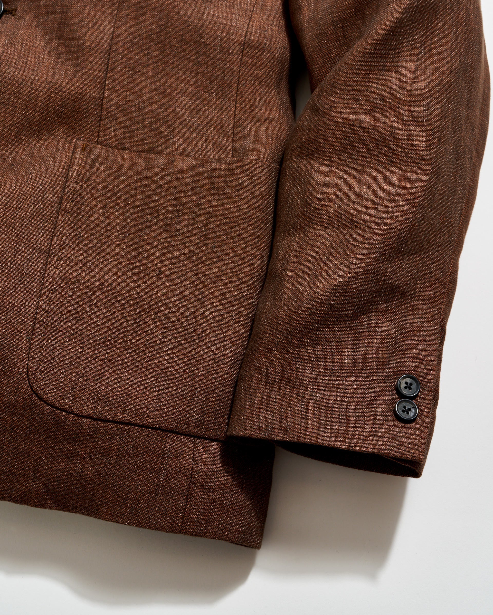 Brown textured fabric with a pocket and button on a white background