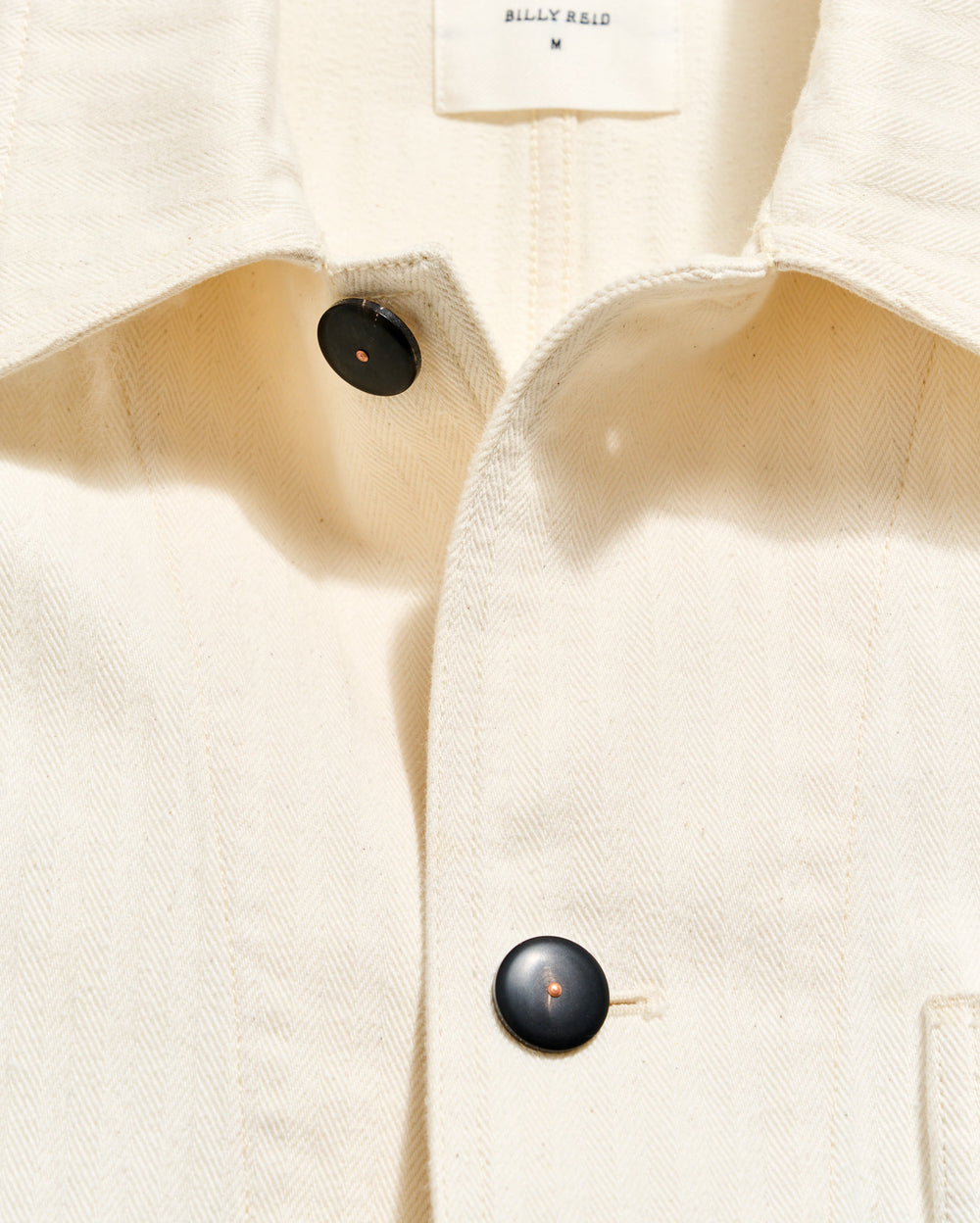 Close-up of a beige coat with black buttons on a white background