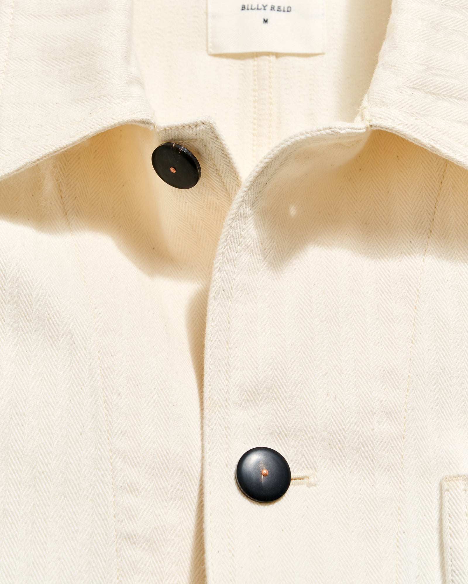 Close-up of a beige coat with black buttons on a white background