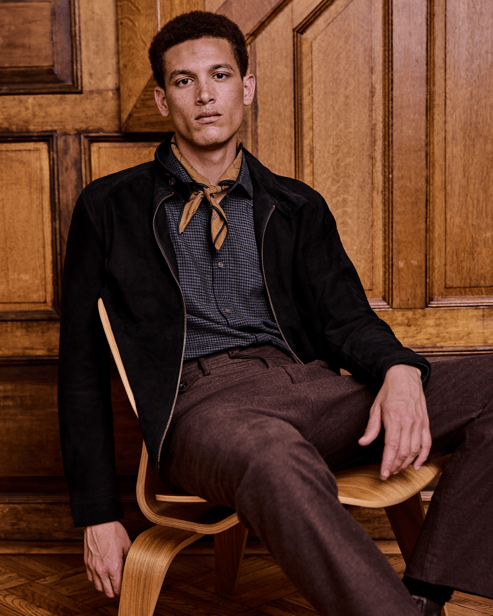 Man sitting on a wooden chair against a wooden paneled wall