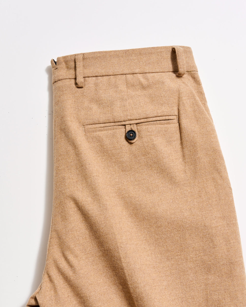 Close-up of beige pants with a button on a light gray background