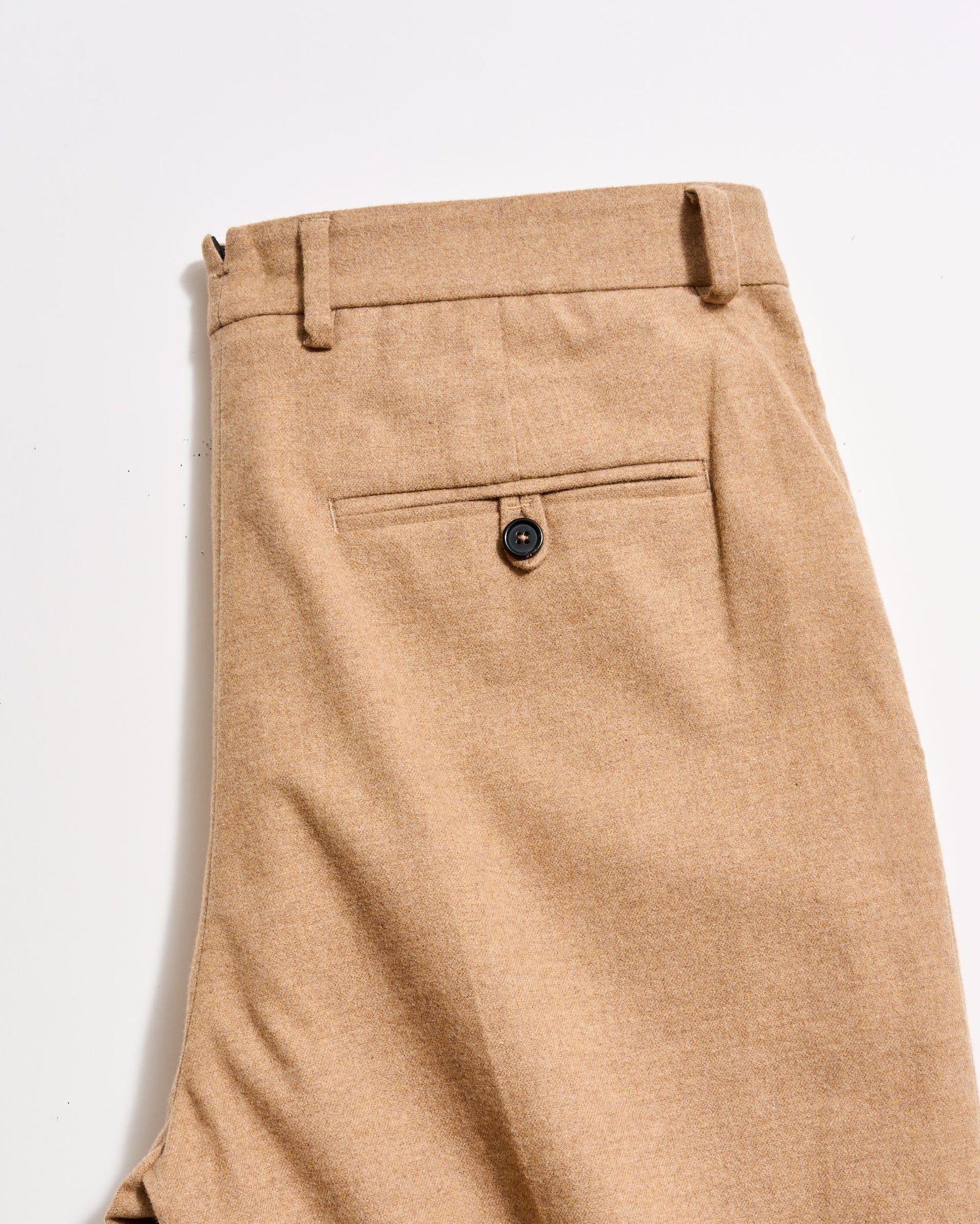 Close-up of beige pants with a button on a light gray background