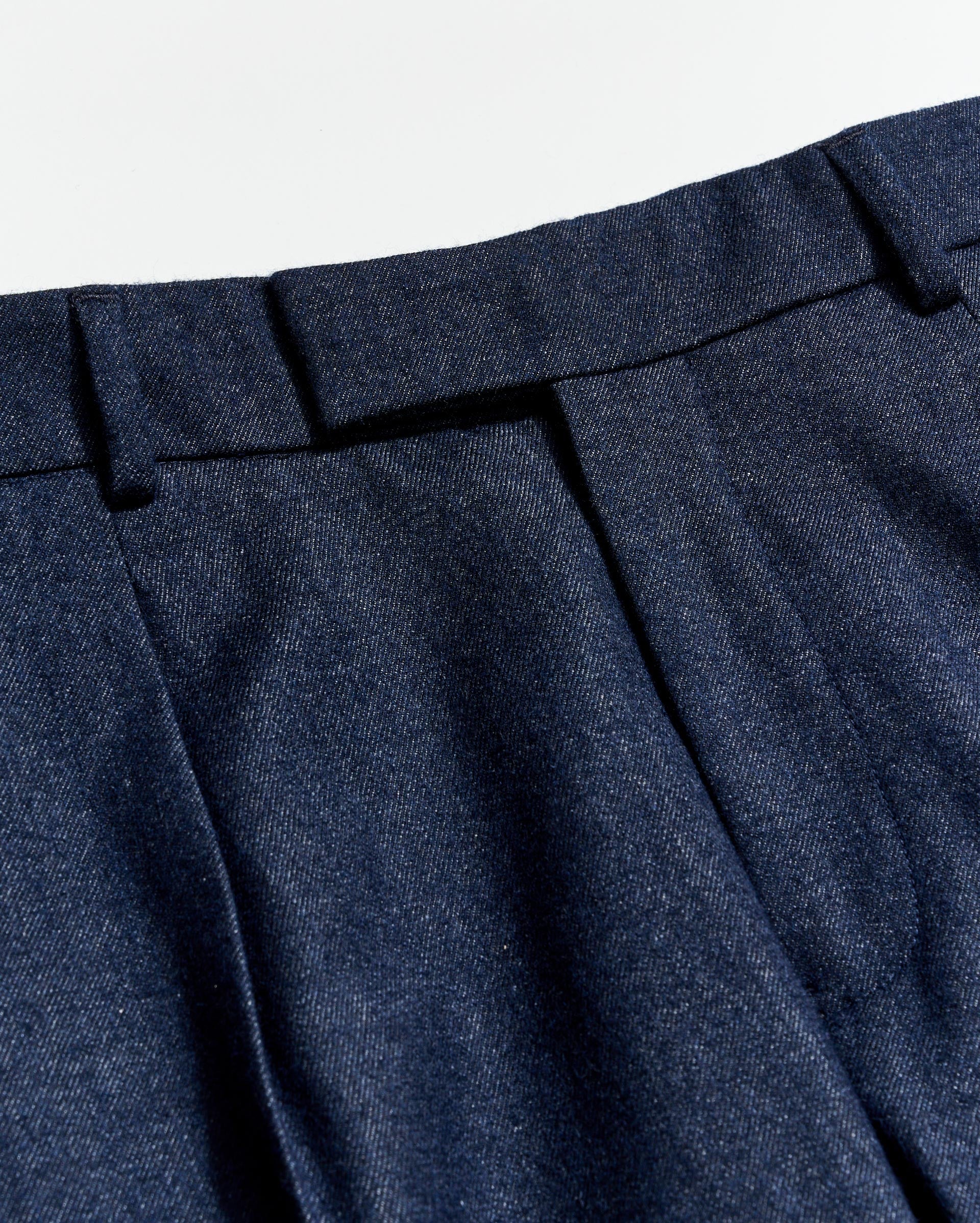 Close-up of blue pleated pants with a light gray background