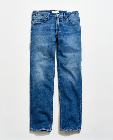 A pair of classic blue denim jeans with a straight-leg cut, five pockets, and a button fly, laid flat on a light background.