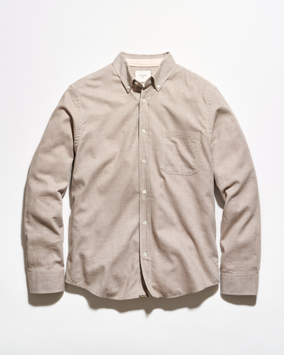 A light beige long-sleeve button-down shirt with a single chest pocket, laid flat against a white background.