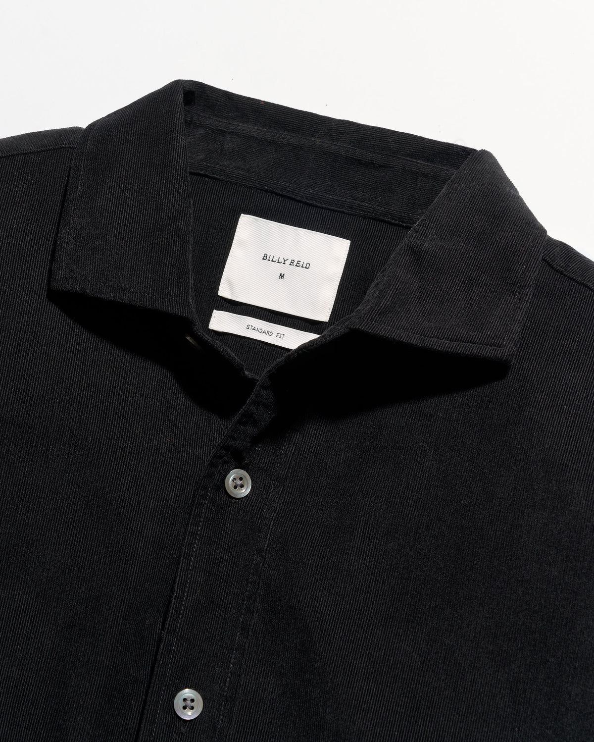 Close-up of a black button-up shirt with a pointed collar and a white neck label reading Billy Reid.