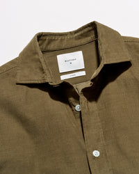 Close-up of a collared button-front shirt in an olive brown fabric, showing the inner neck label that reads BILLY RUSK.