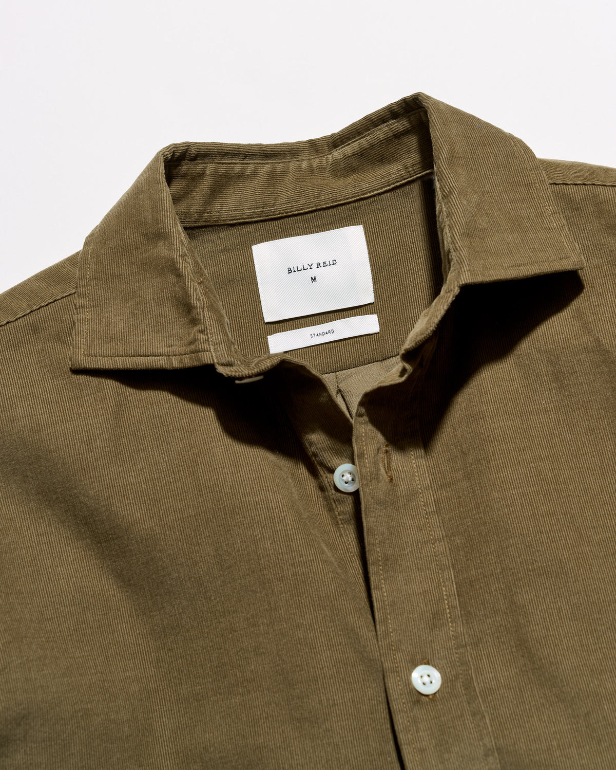 Close-up of a collared button-front shirt in an olive brown fabric, showing the inner neck label that reads BILLY RUSK.