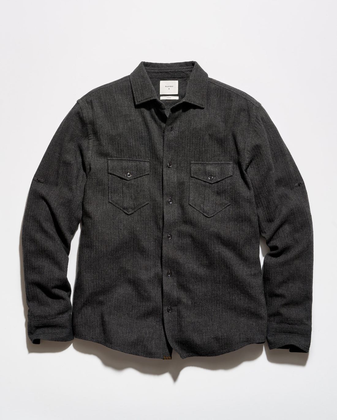 A dark charcoal gray textured long-sleeve button-up shirt with two buttoned chest pockets, laid flat against a light gray background.