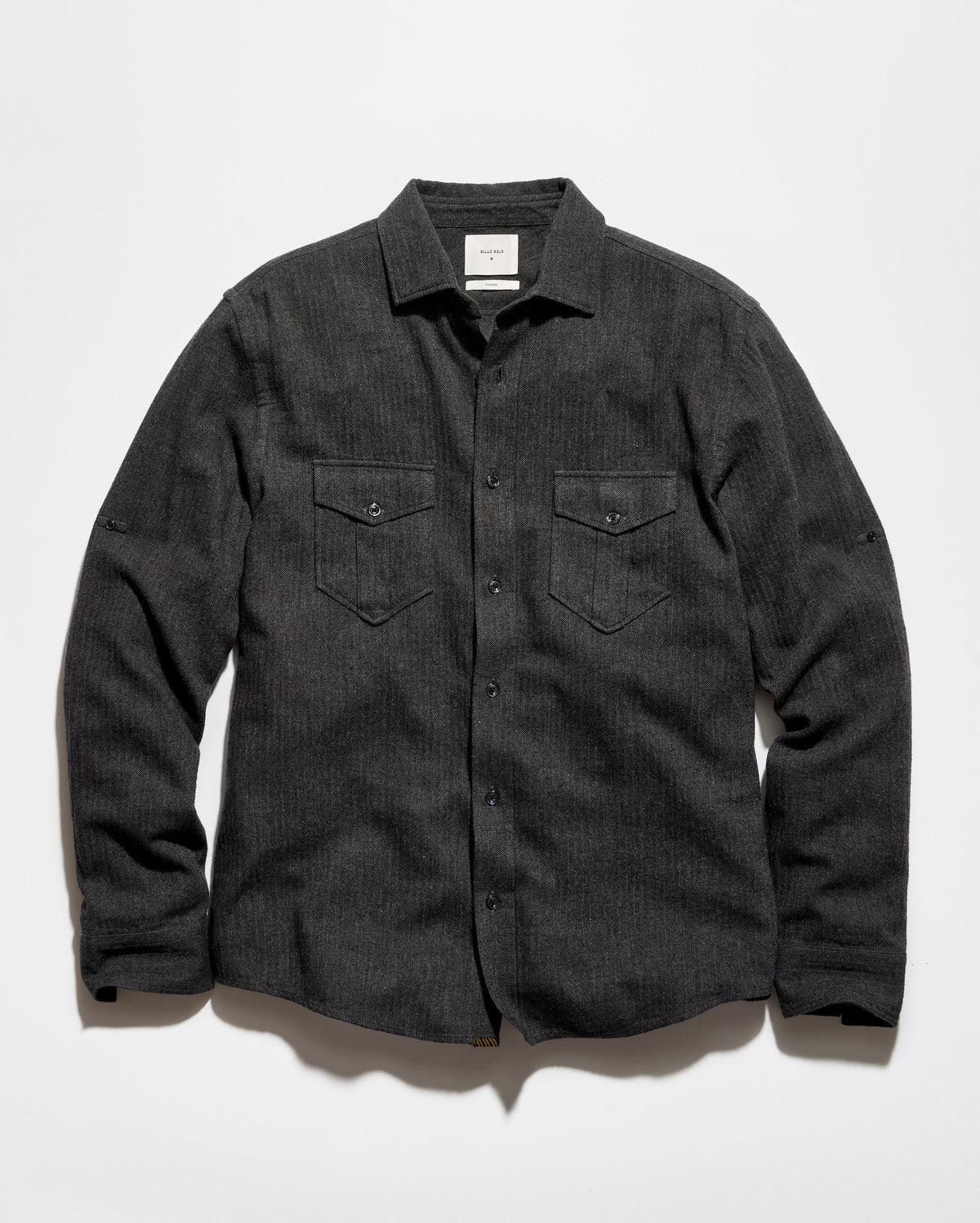 A dark charcoal gray textured long-sleeve button-up shirt with two buttoned chest pockets, laid flat against a light gray background.