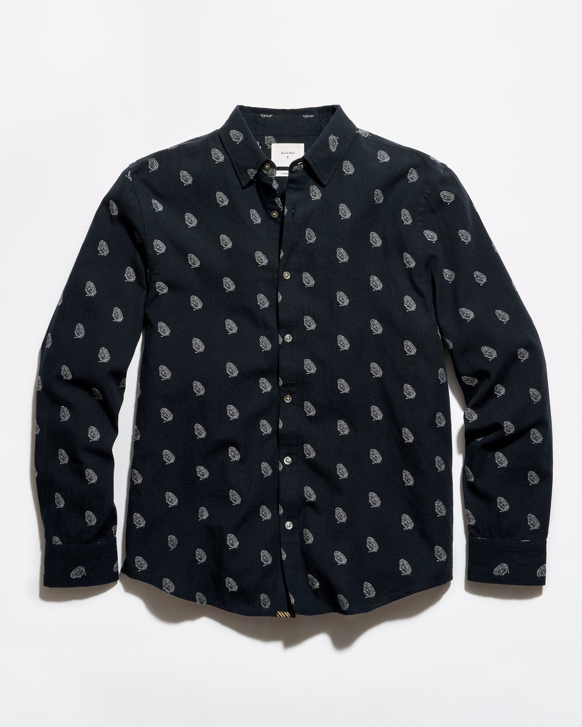A long-sleeve button-up shirt in black with a repeating small white paisley pattern, laid flat against a white background.