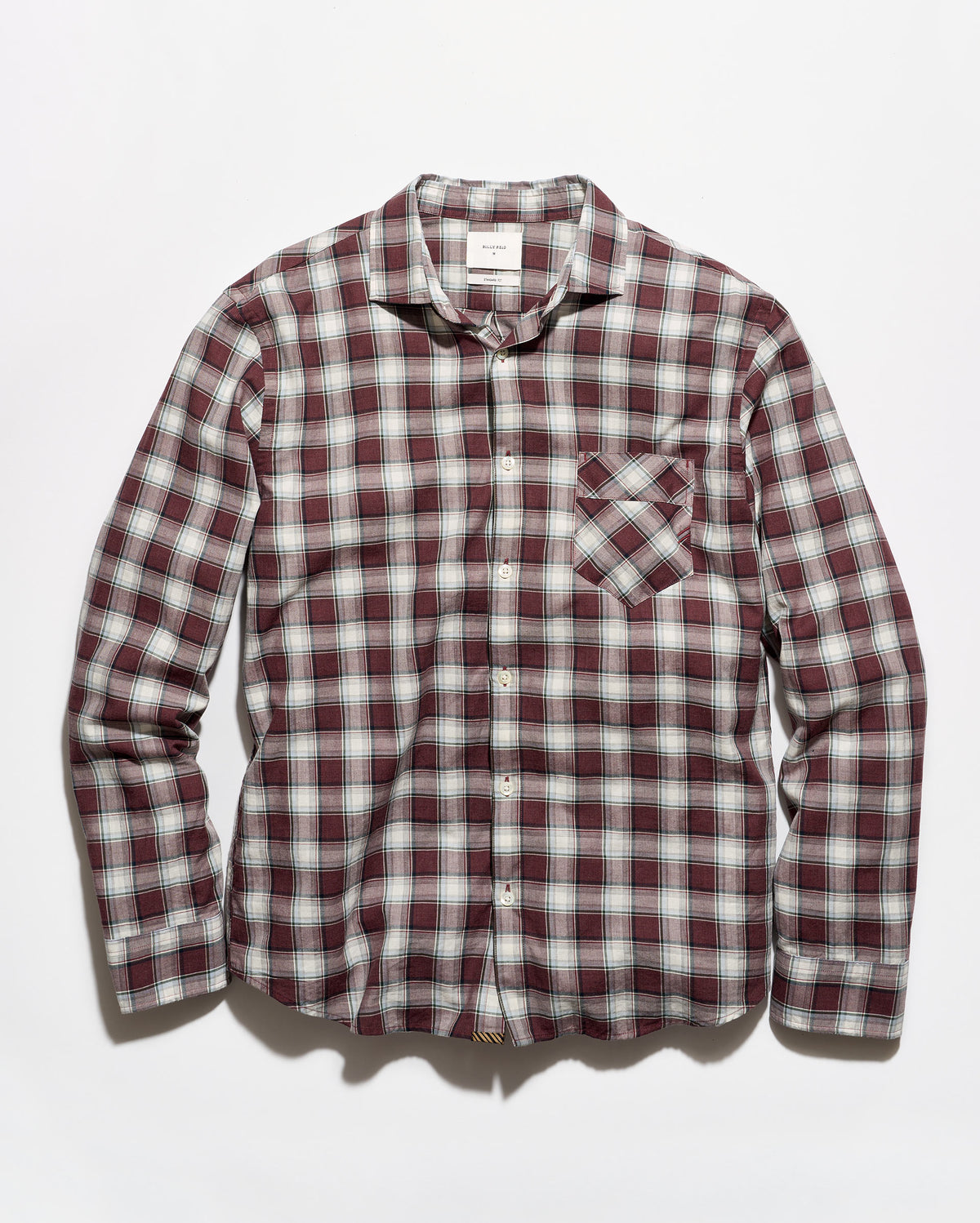 A long-sleeve button-up plaid shirt in a burgundy, white, and gray checkered pattern, featuring a single chest pocket, laid flat against a light gray background.