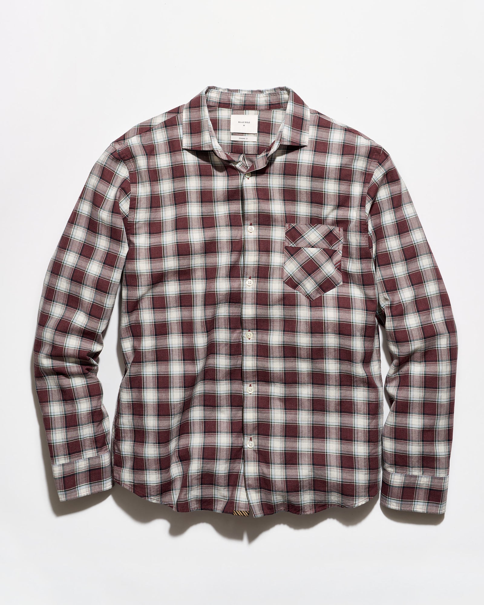 A long-sleeve button-up plaid shirt in a burgundy, white, and gray checkered pattern, featuring a single chest pocket, laid flat against a light gray background.