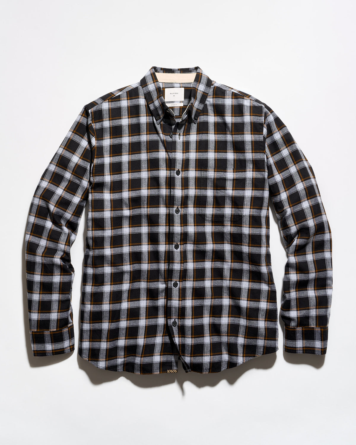 A long-sleeve button-down plaid shirt in black, white, and thin orange stripes, laid flat against a light gray background.
