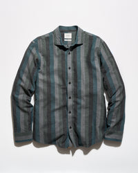 A long-sleeve button-up shirt with vertical stripes in slate blue, gray, and charcoal, laid flat against a white background.