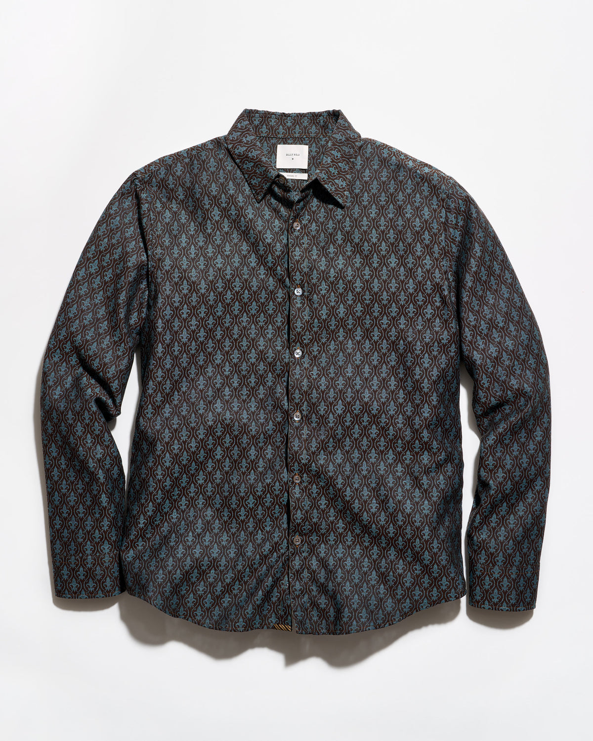 A long-sleeve button-up shirt with a dark charcoal gray and black base, featuring a repeating small geometric pattern in muted blue and brown tones, laid flat against a light gray background.
