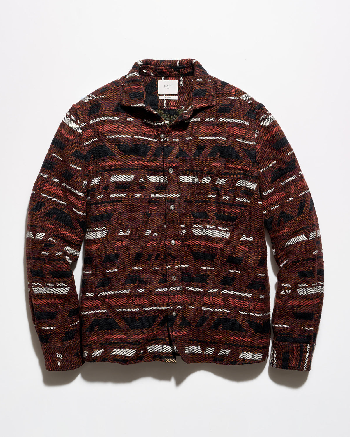 A long-sleeve button-up shirt with a geometric pattern in dark red, black, and off-white, laid flat against a light gray background.