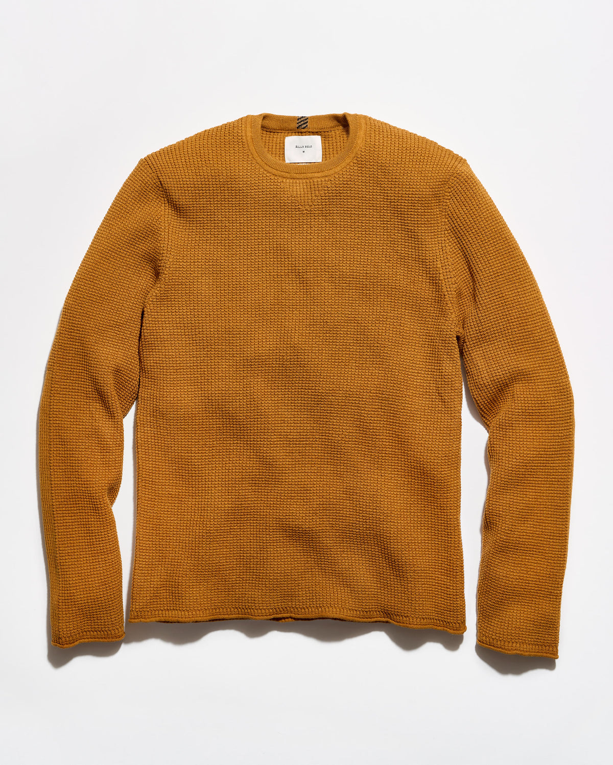 A textured waffle-knit crewneck sweater in a warm mustard yellow color, laid flat against a clean white background.