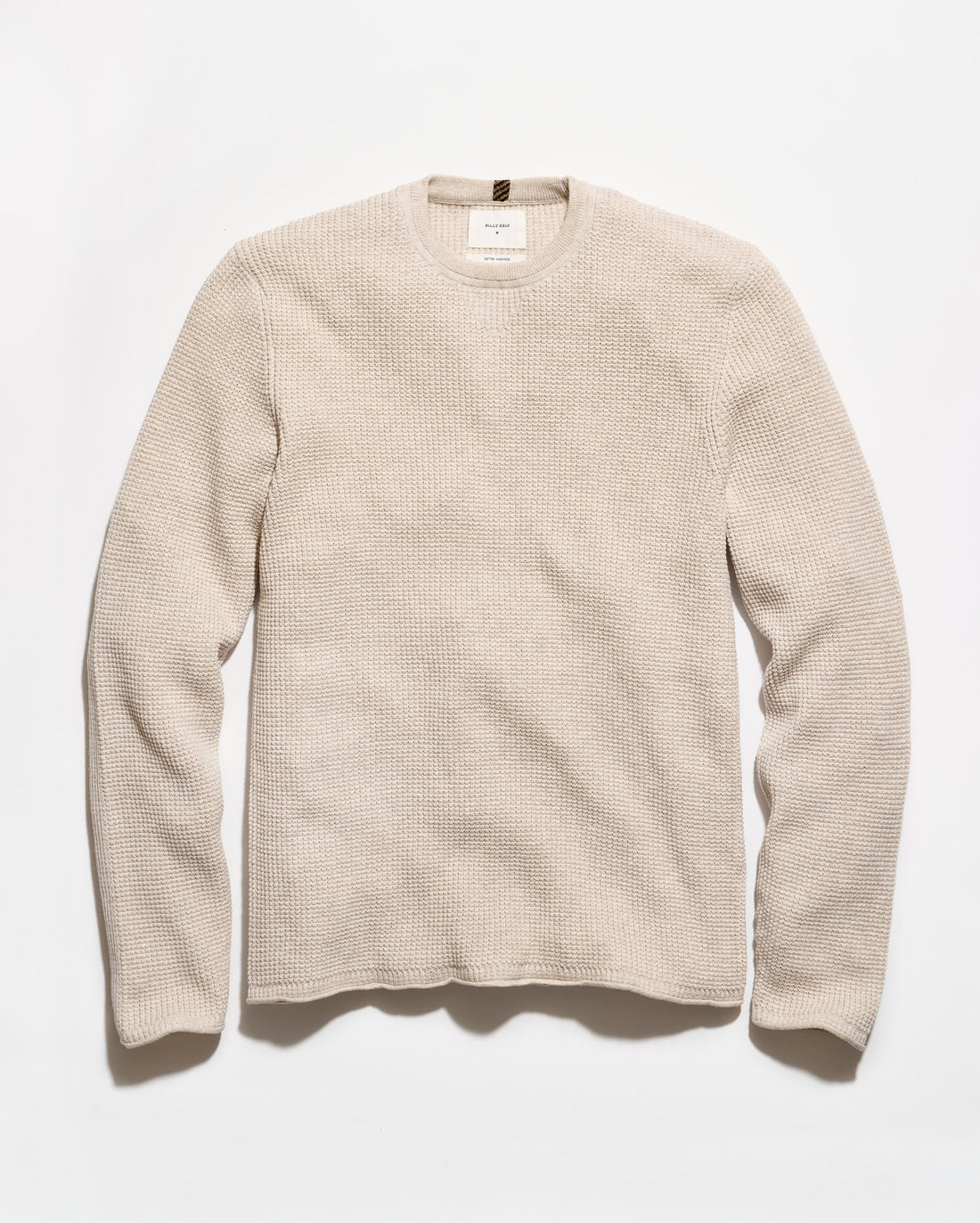 A light beige crewneck sweater with a textured waffle knit pattern, laid flat against a clean white background.