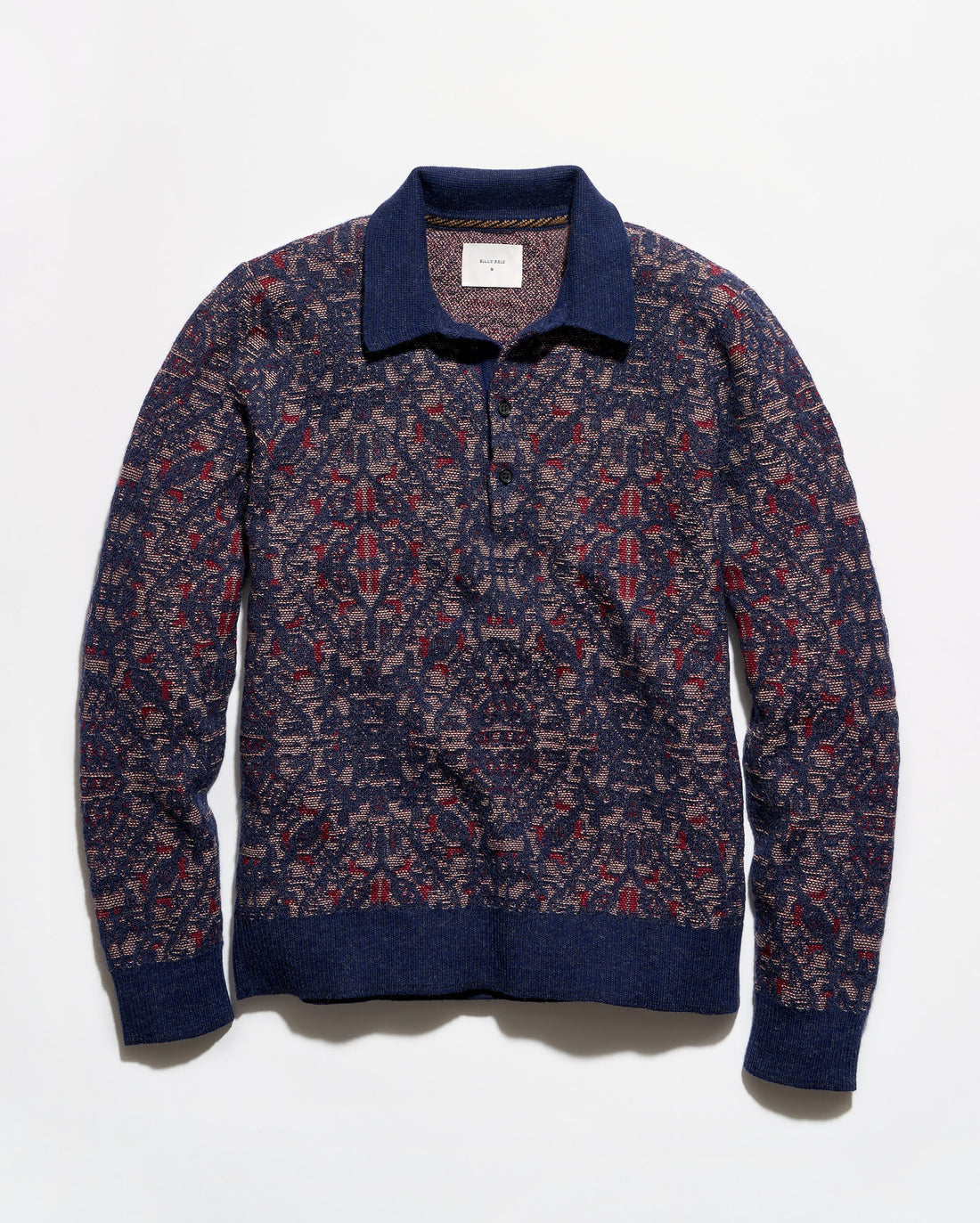 A long-sleeve knit polo-style sweater with an intricate geometric pattern in navy blue, burgundy red, and beige, featuring solid navy ribbed trim on the collar, cuffs, and hem.