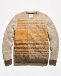 A crewneck knit sweater with a textured herringbone pattern, featuring a beige body, mustard yellow chest panel, and brown and gray striped lower section, laid flat against a white background.