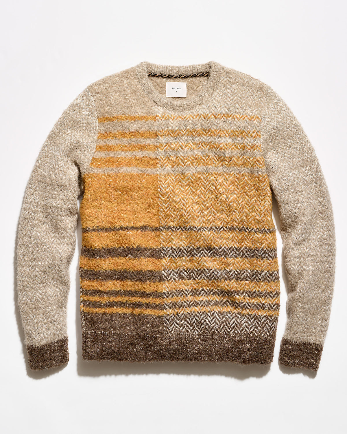 A crewneck knit sweater with a textured herringbone pattern, featuring a beige body, mustard yellow chest panel, and brown and gray striped lower section, laid flat against a white background.