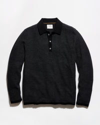 A black long-sleeve polo shirt with a textured knit pattern, laid flat against a light gray background.