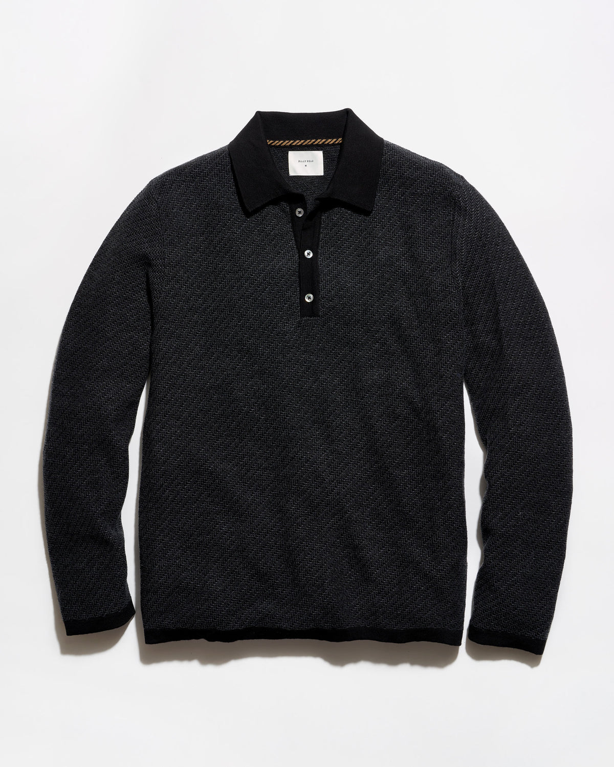 A black long-sleeve polo shirt with a textured knit pattern, laid flat against a light gray background.
