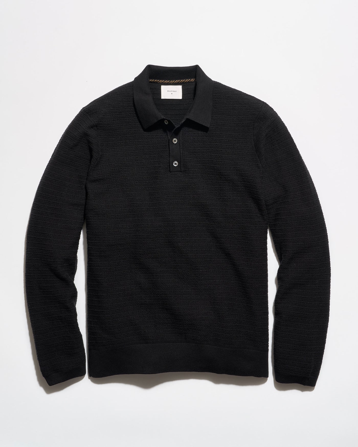 A black long-sleeve knit polo shirt with a textured horizontal rib pattern, laid flat against a clean white background.