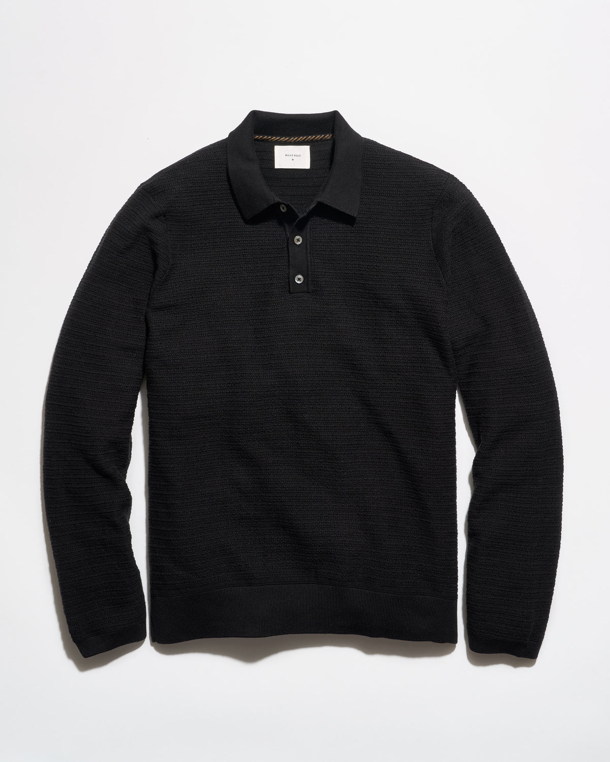 A black long-sleeve knit polo shirt with a textured horizontal rib pattern, laid flat against a clean white background.
