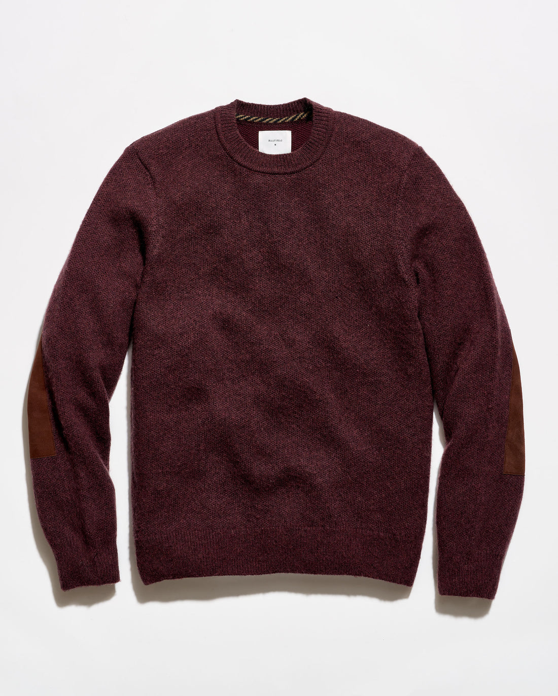 A crewneck sweater in a deep burgundy color with brown patchwork elbow patches, laid flat against a white background.