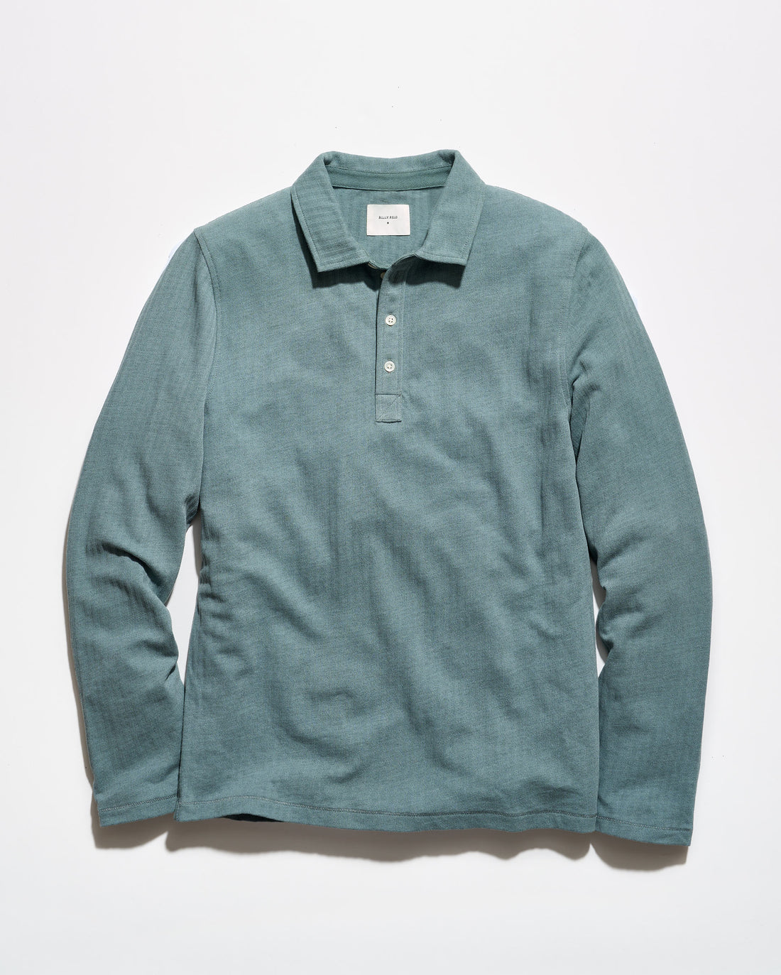 A long-sleeve polo shirt in a muted teal-green color, laid flat against a clean white background.