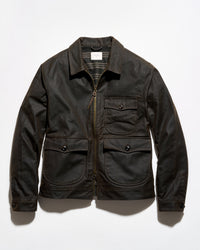 A dark brown waxed canvas utility jacket with a front zipper, two chest flap pockets, and two large lower hand-warmer pockets, laid flat against a white background.
