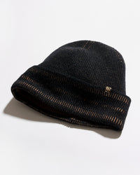 A black knit beanie hat with a folded cuff, featuring a small gold embroidered logo on the side, photographed on a clean white background with a soft shadow.