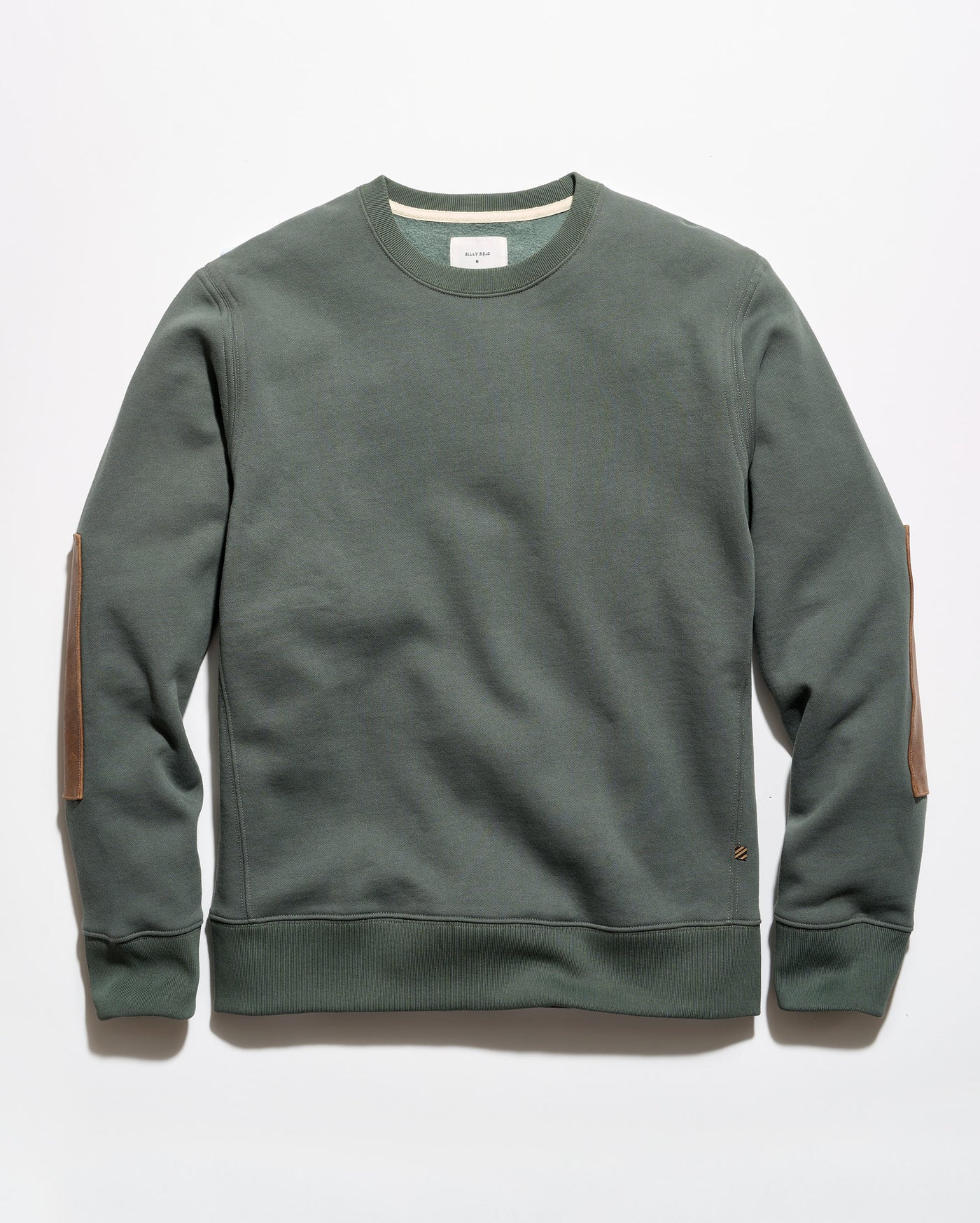 An olive green crewneck sweatshirt with brown leather elbow patches, laid flat against a light gray background.