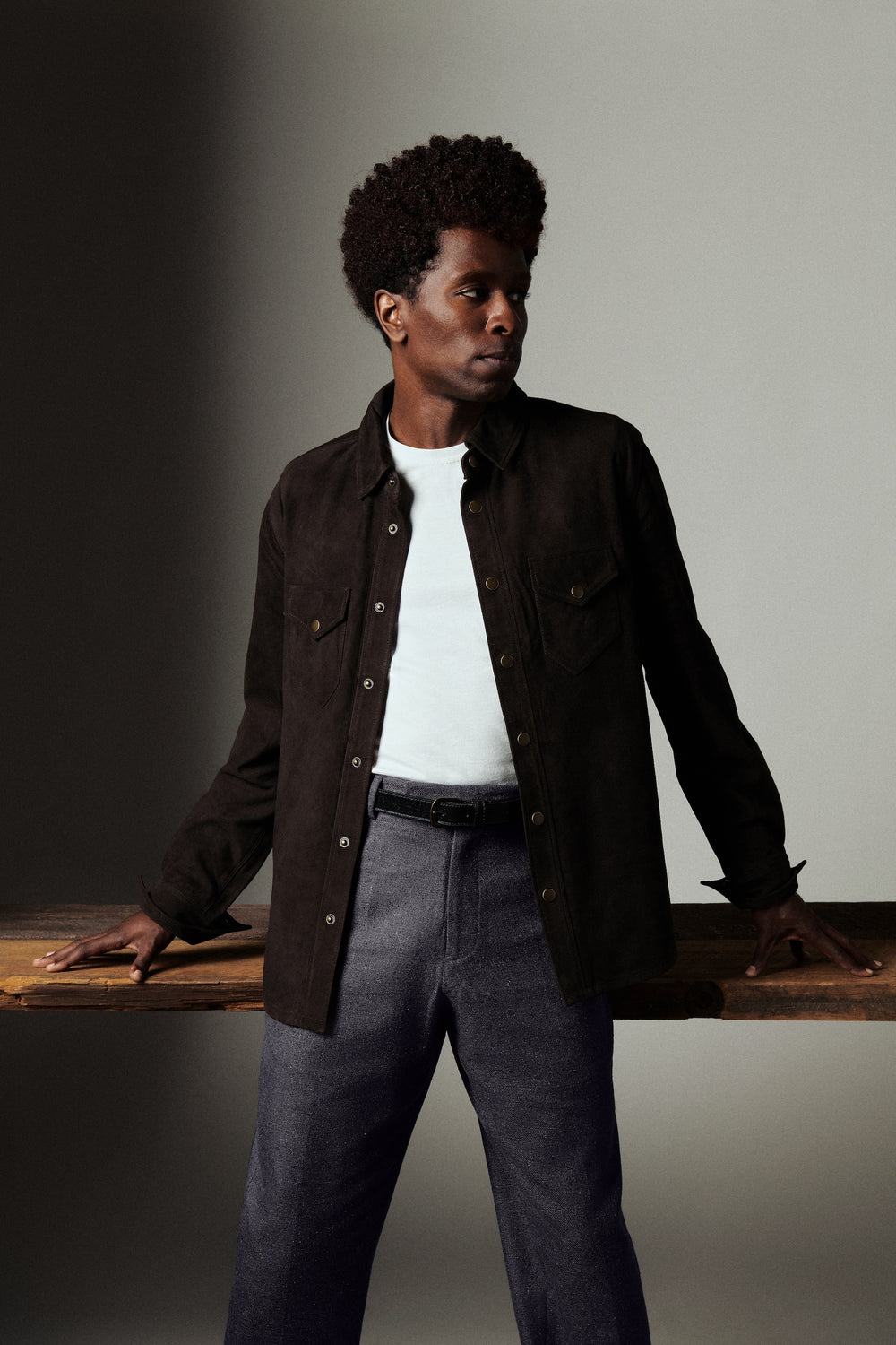 Man wearing a dark jacket and white shirt against a neutral background