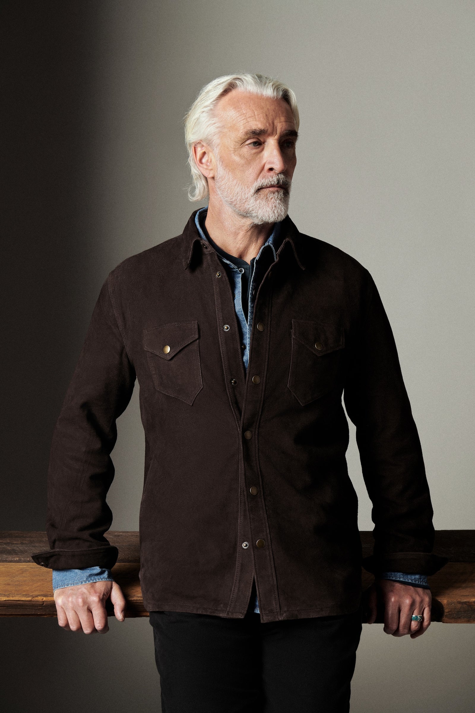 Man wearing a dark brown jacket against a neutral background