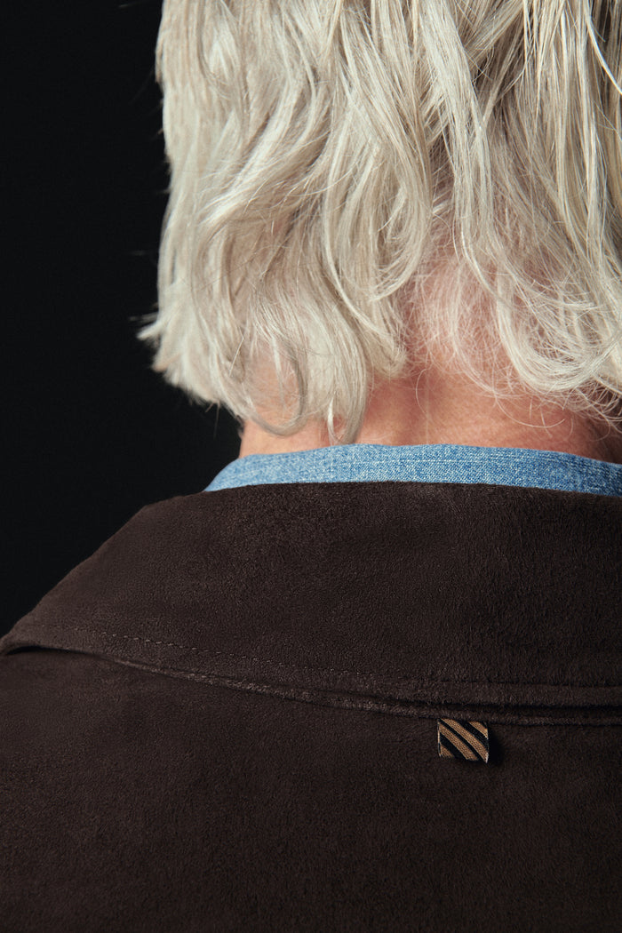 Close-up of a person wearing a dark jacket with a visible brand logo against a black background