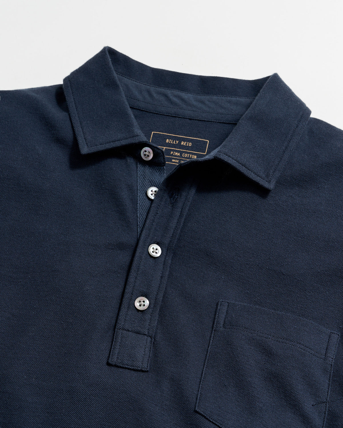 Navy polo shirt with brand label on a light gray background