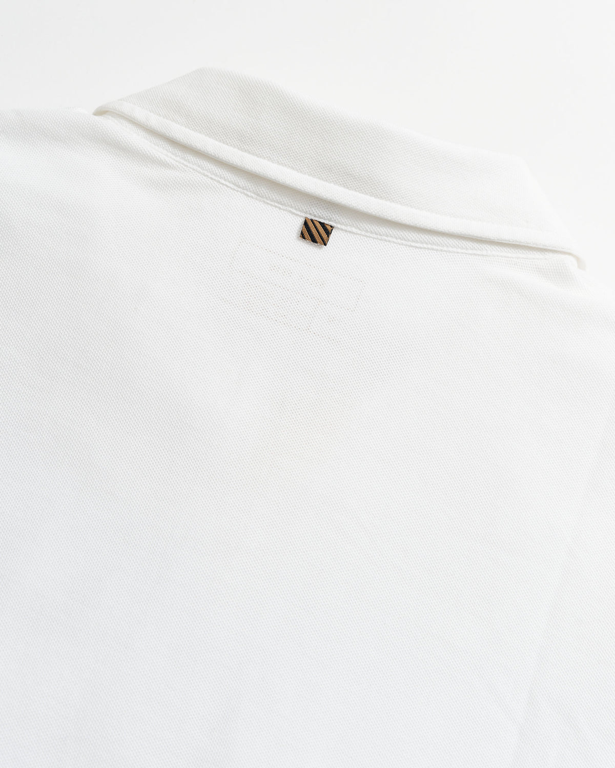 White shirt with a small logo on a light gray background