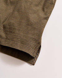 A close-up of the hem of a brown and black striped fabric, possibly a shirt or sleeve, set against a light background. The stripes run horizontally, and the stitching is visible at the edge.