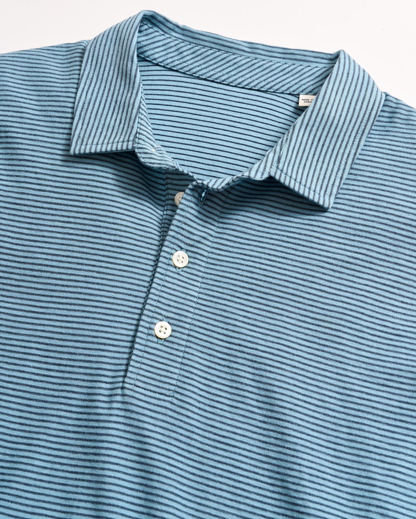 Blue short-sleeved polo shirt with thin horizontal dark blue stripes, white buttons, and a collar, laid flat on a white surface.