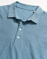 Blue short-sleeved polo shirt with thin horizontal dark blue stripes, white buttons, and a collar, laid flat on a white surface.