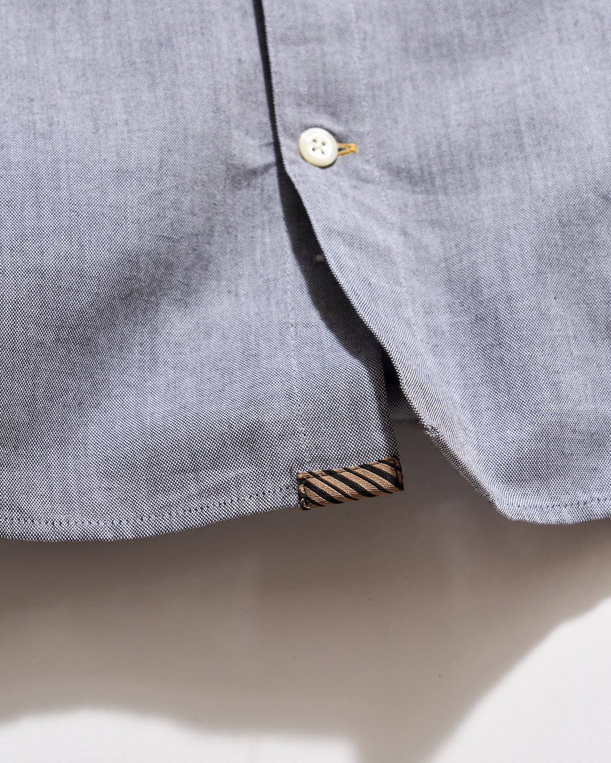 Close-up of a gray shirt collar with a button and label on a light background