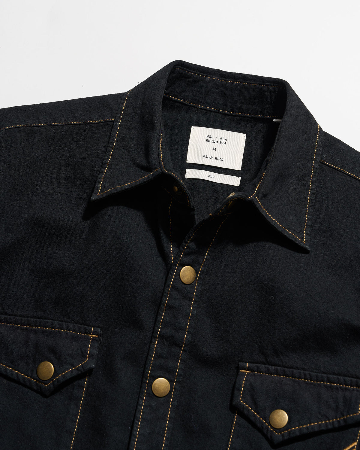 Black denim jacket with gold buttons on a white background