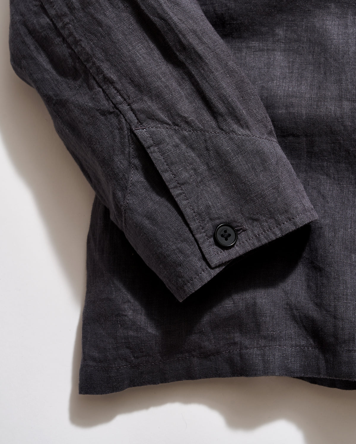 Dark gray shirt with button on a light beige background