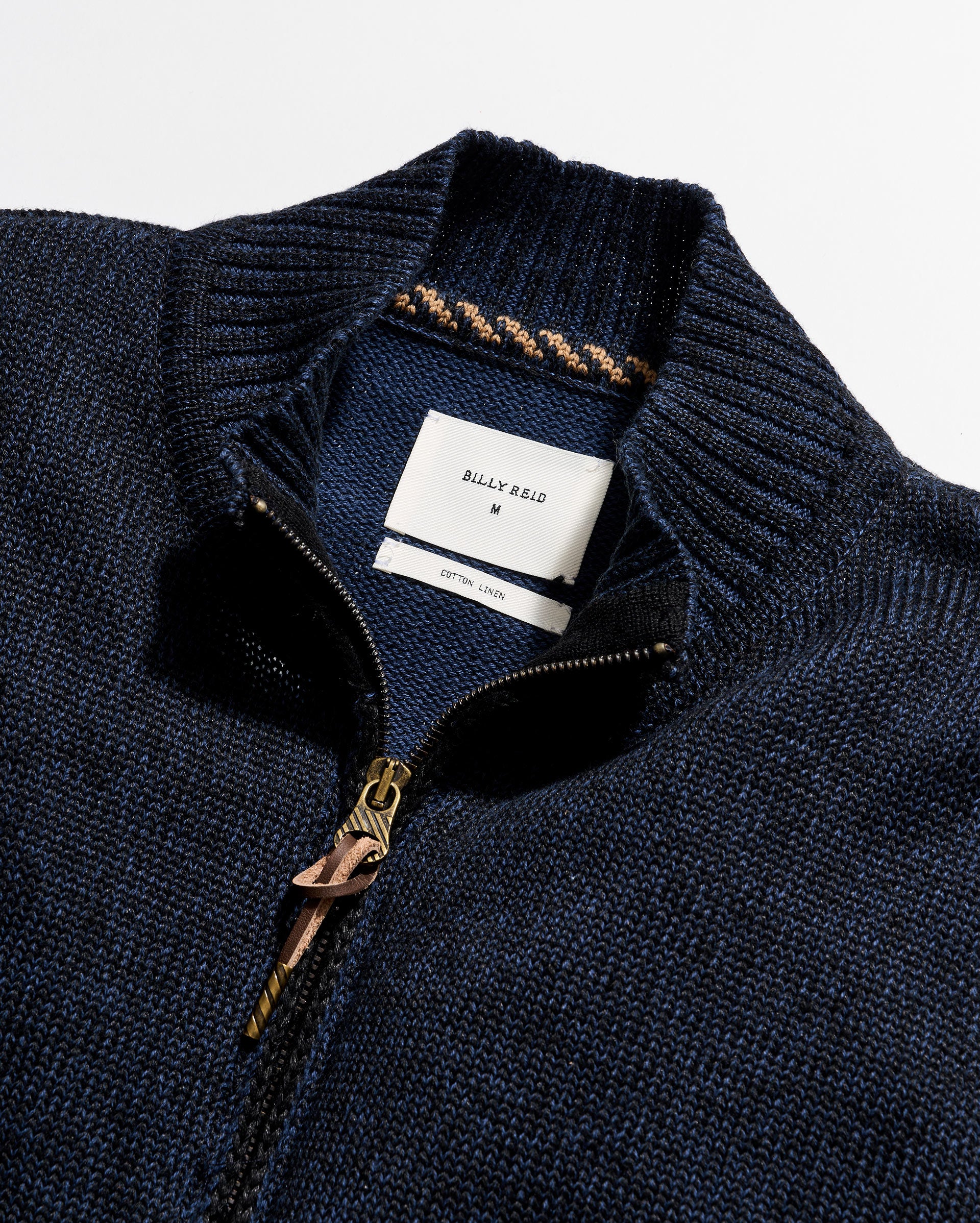 Close-up of a navy blue sweater with a brand label on a white background